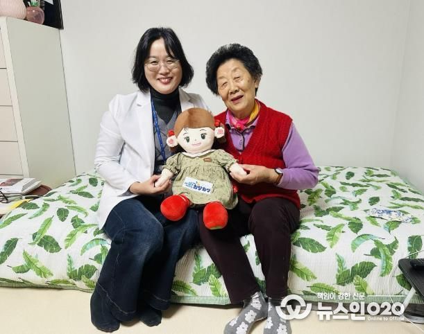 화성시동탄보건소 관계자와 독거 어르신이 AI 돌봄로봇 ‘효돌이’를 함께 들고 환하게 웃고 있다